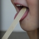 An image of a tongue depressor in child's mouth for a throat exam.